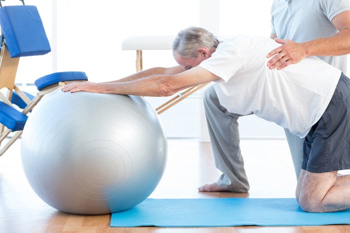 Physiotherapist assisting an elderly patient with balance and stretching exercises