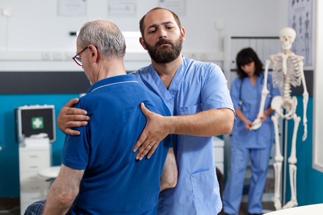 Physiotherapist assisting an elderly patient during shoulder rehabilitation therapy