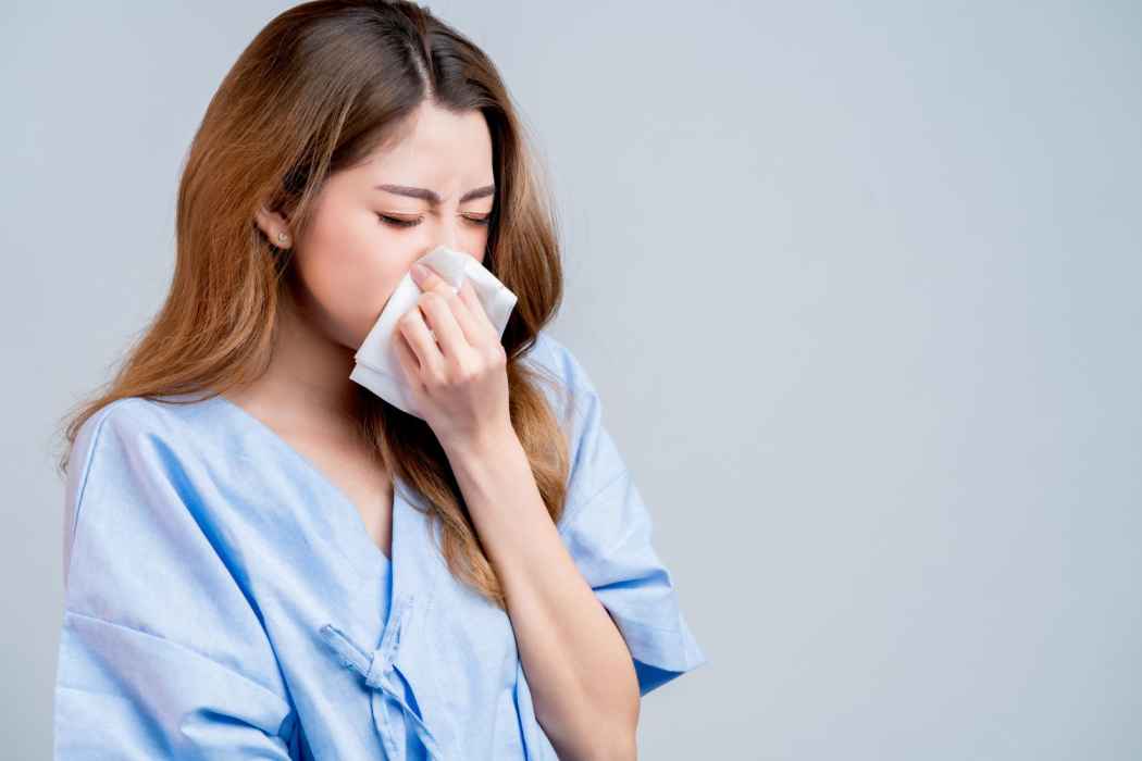 Woman holding a tissue and experiencing nasal congestion or cold symptoms