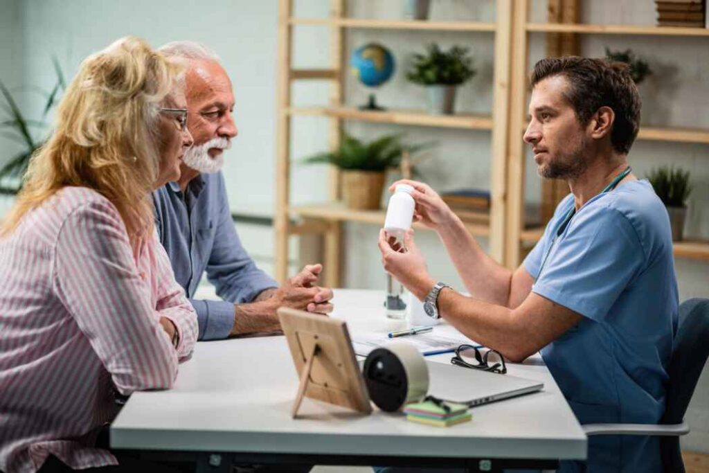 Doctor explaining medication to an elderly couple during a medical consultation in a clinic.