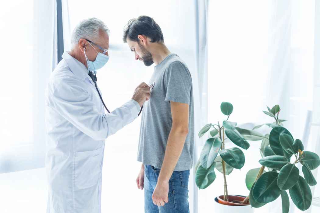 Doctor examining a male patient’s chest with a stethoscope during a routine checkup