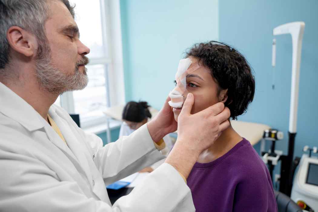 Doctor examining a patient with nasal bandages during a follow-up visit