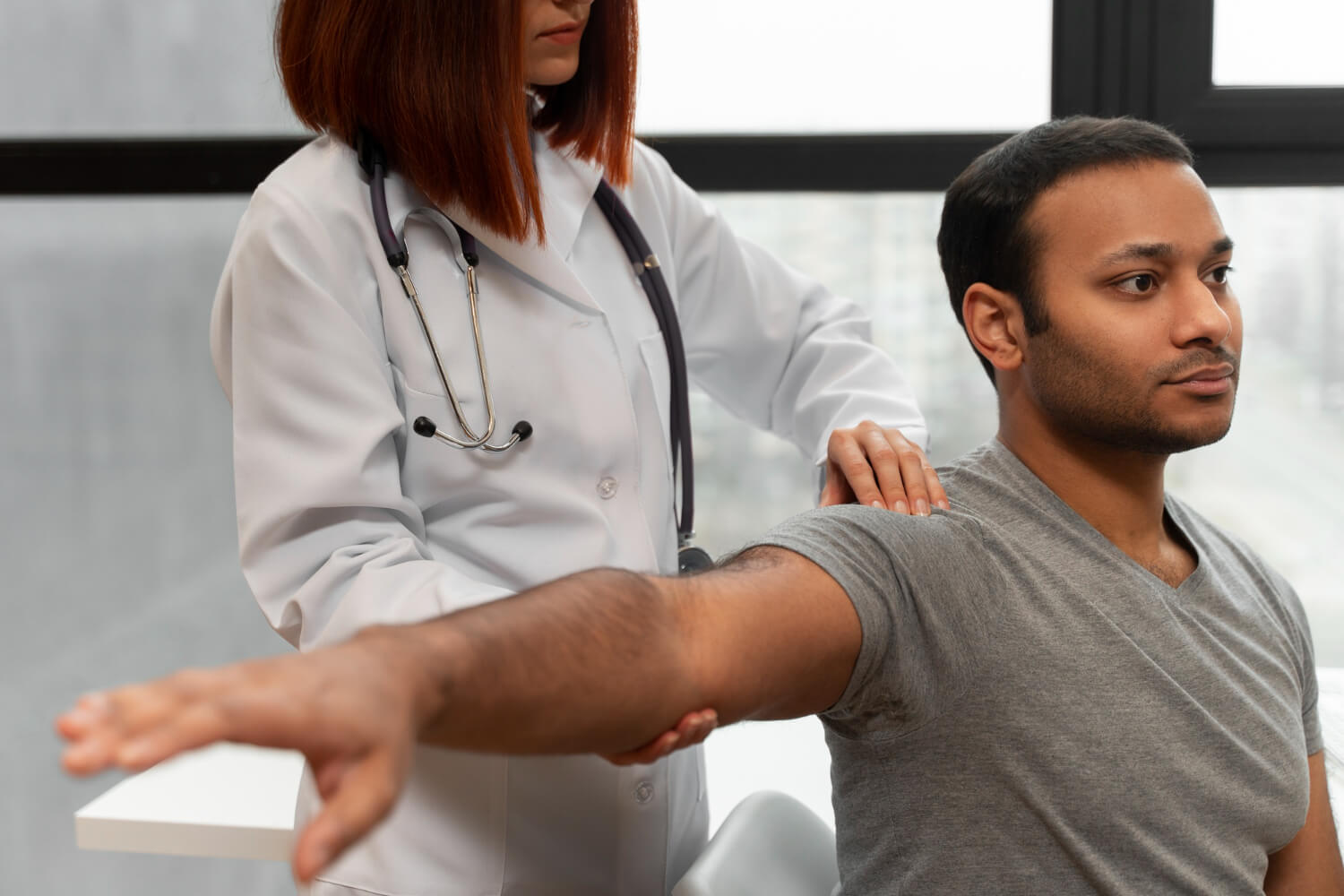 Doctor assessing shoulder and arm mobility of a male patient during a clinical examination