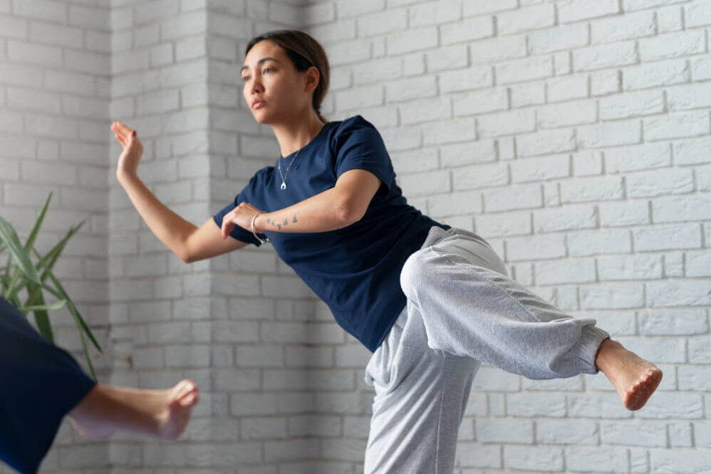 Woman performing balance and mobility physiotherapy exercise on a yoga mat in a clinic