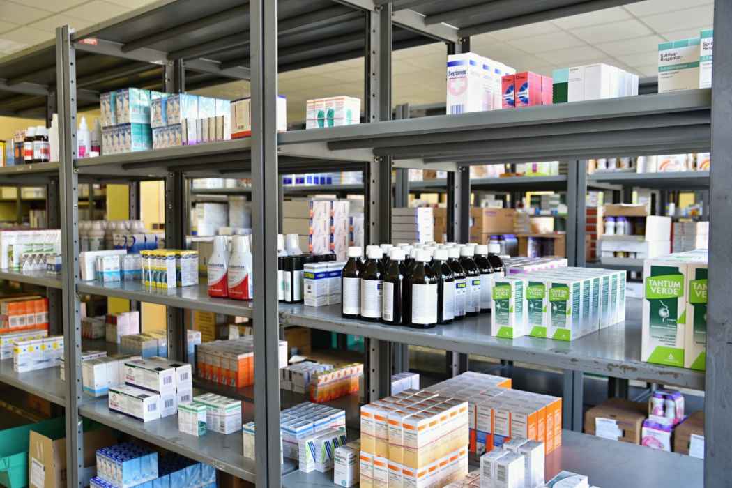 Shelves stocked with boxed medications and pharmaceutical supplies in a pharmacy storage area