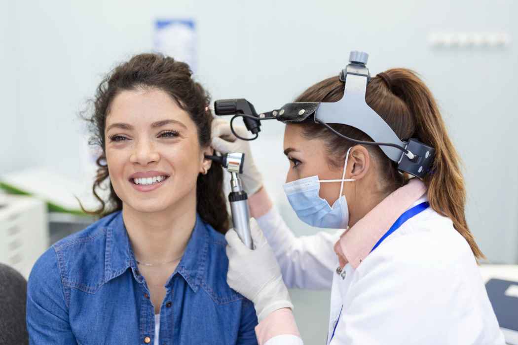 Doctor examining a woman’s ear with an otoscope during an ENT checkup