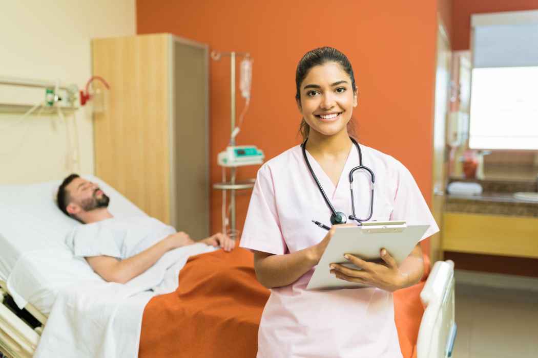 Nurse holding a clipboard while monitoring a patient resting in a hospital bed