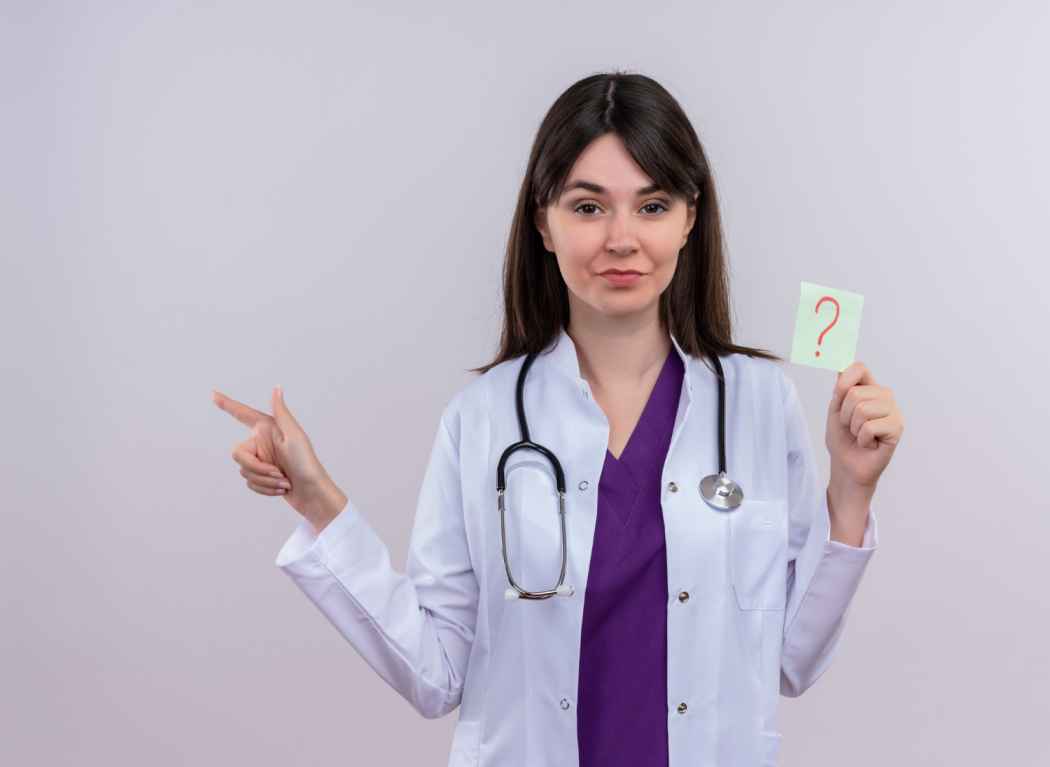 Female doctor holding a question mark card and pointing sideways, representing medical questions and patient guidance