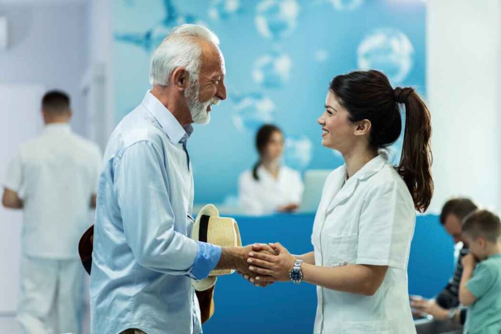 Elderly patient greeting a female healthcare professional at a hospital or clinic reception area