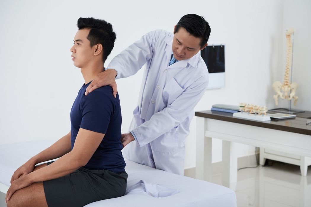 Doctor assessing patient posture and spinal alignment during examination