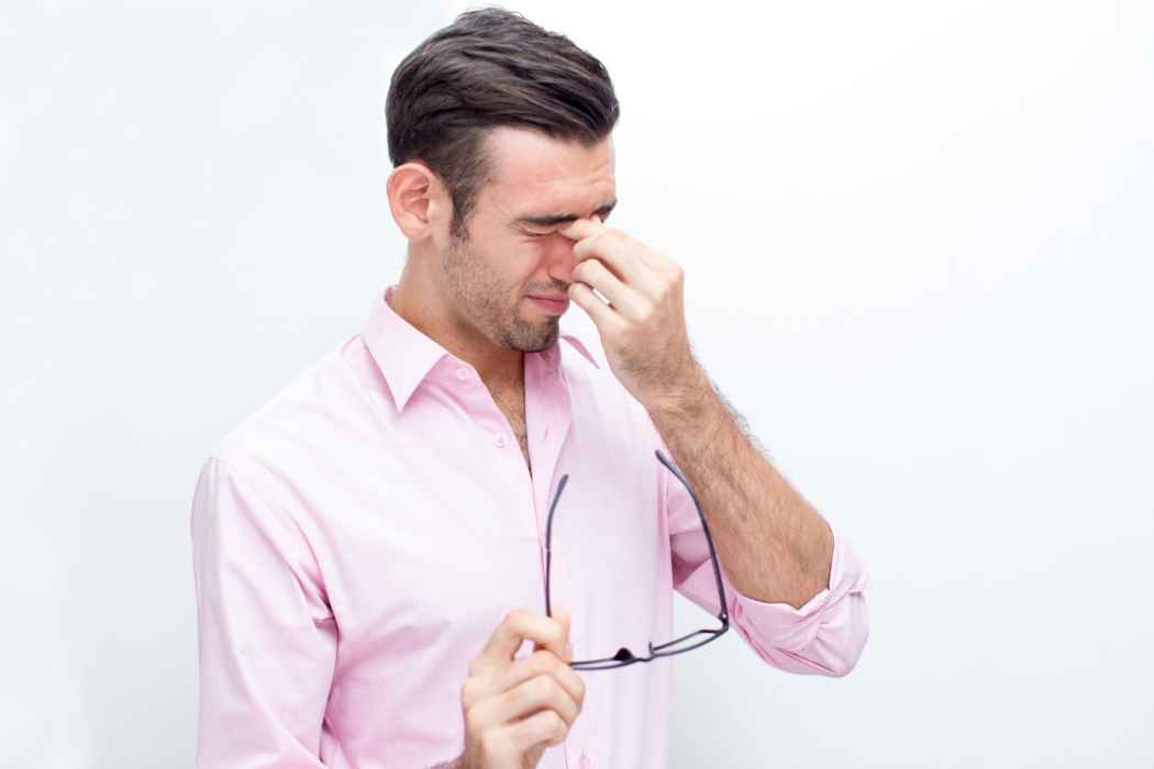 Man pressing the bridge of his nose due to sinus pain or facial pressure