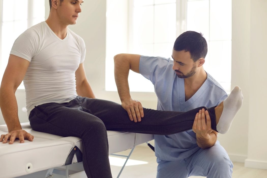 Physiotherapist examining leg movement during rehabilitation therapy