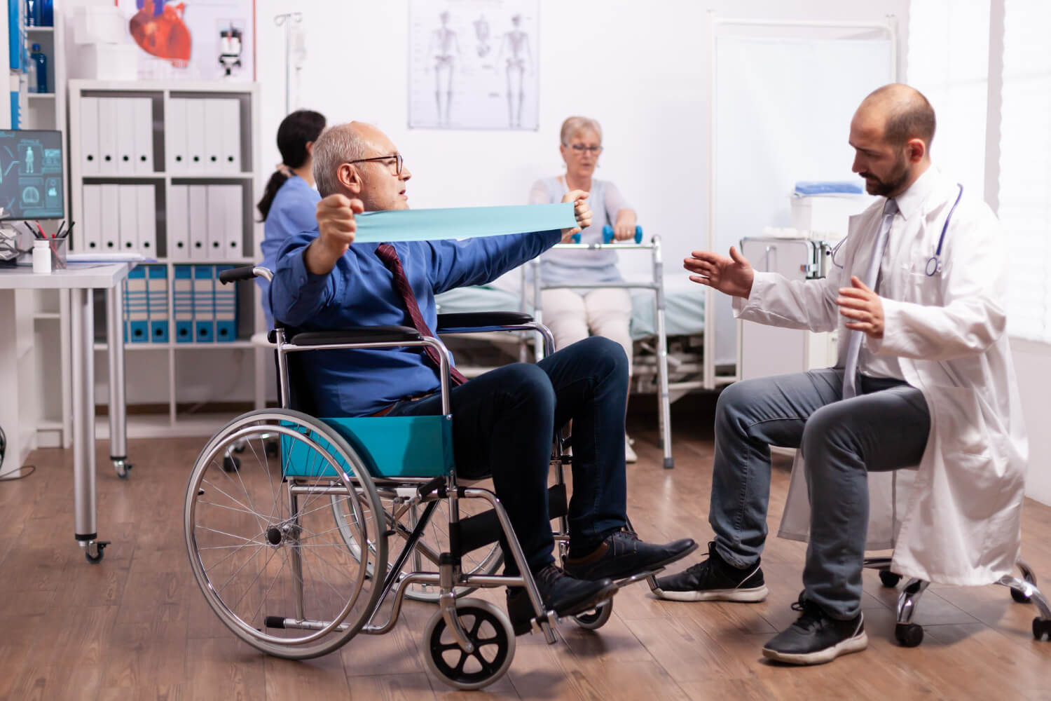 Elderly patient in a wheelchair performing resistance band physiotherapy under medical supervision