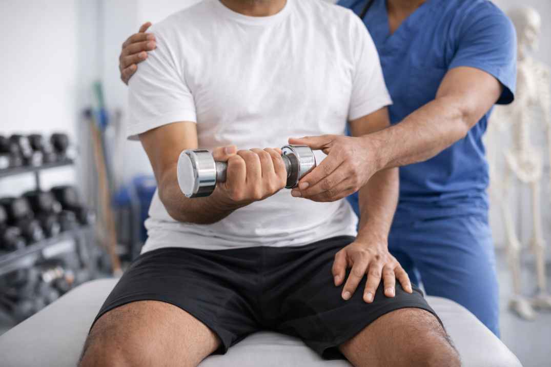 Physiotherapist guiding a patient through supervised arm strengthening exercise using a dumbbell