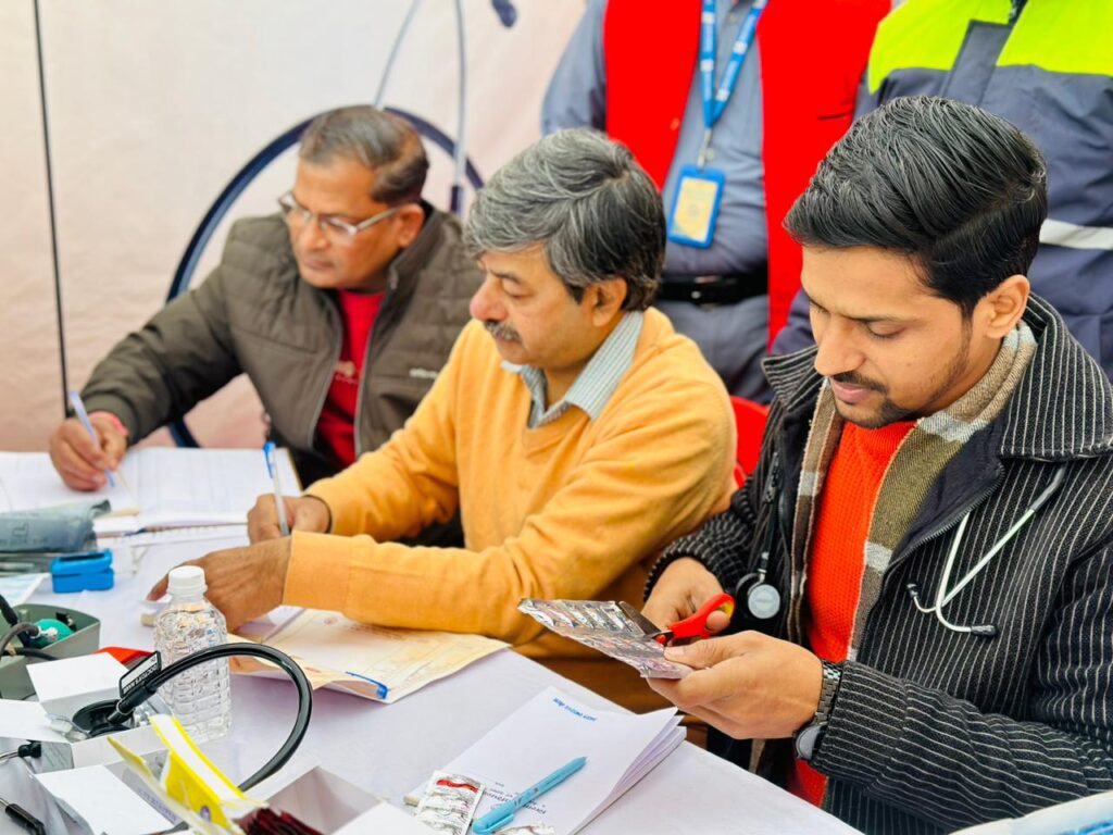 Doctors recording patient details and preparing medicines during a community health screening camp