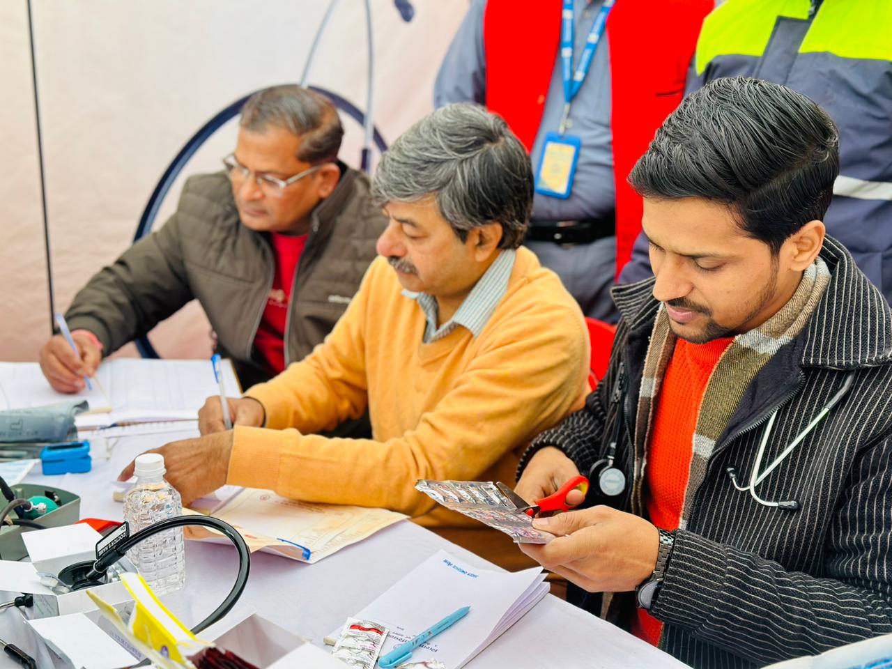 Doctors recording patient details and preparing medicines during a community health screening camp