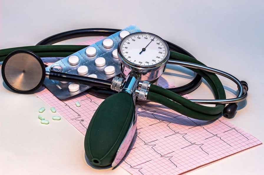 Blood pressure monitor with stethoscope and tablets placed on an ECG report