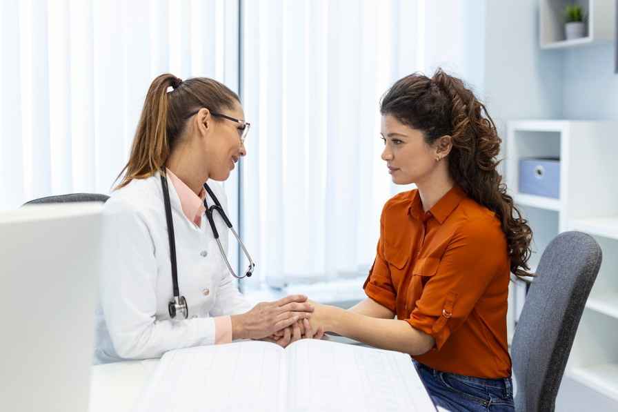 Doctor holding a patient’s hands during a compassionate medical consultation