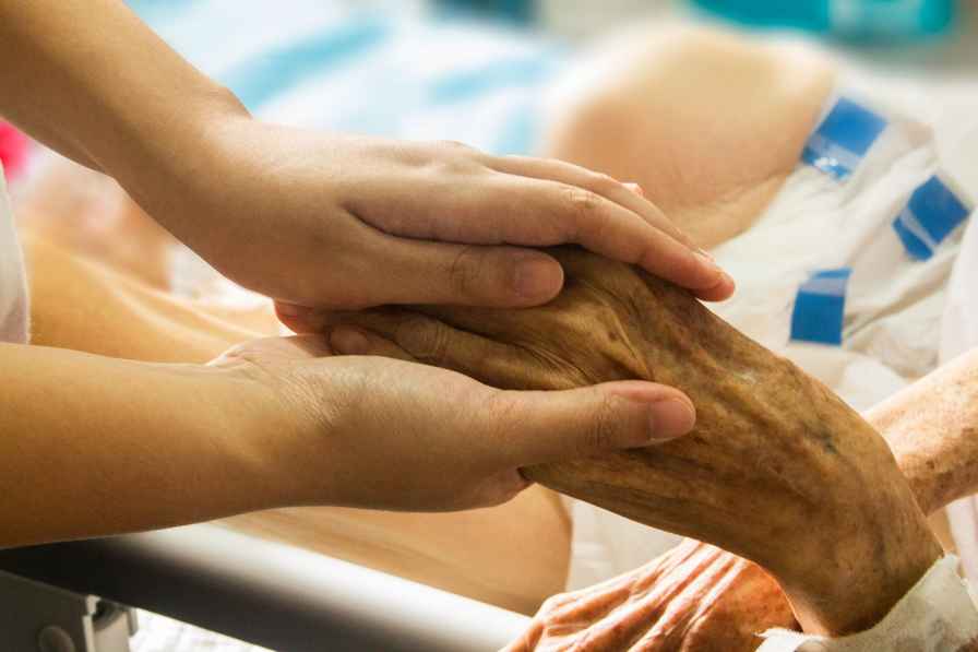 Caregiver holding the hand of an elderly patient, showing compassion and support in a healthcare setting