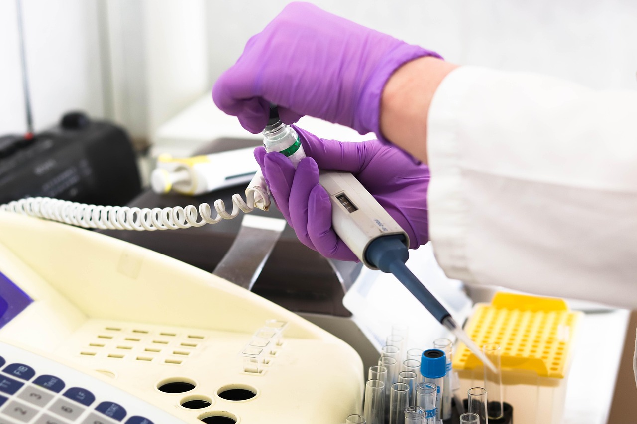 Laboratory technician using a micropipette to handle a sample vial during medical testing.