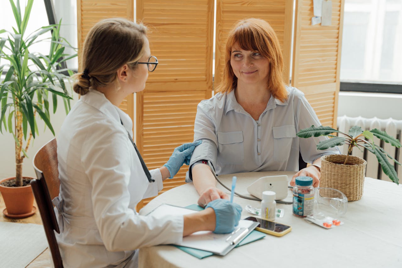 Healthcare professional measuring a woman’s blood pressure during a routine medical checkup.