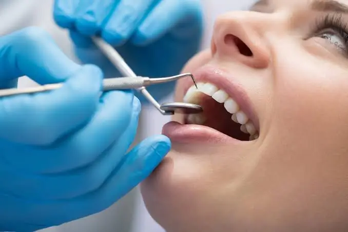 Dentist performing a professional dental examination using a dental mirror and explorer to check teeth and gums during a routine oral health checkup.