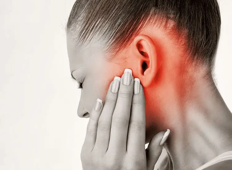 Patient experiencing severe TMJ pain while holding the jaw near the ear, indicating temporomandibular joint disorder and facial discomfort.