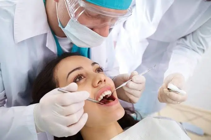 Dentist performing a comprehensive dental examination using a dental mirror and explorer during a routine oral health checkup.