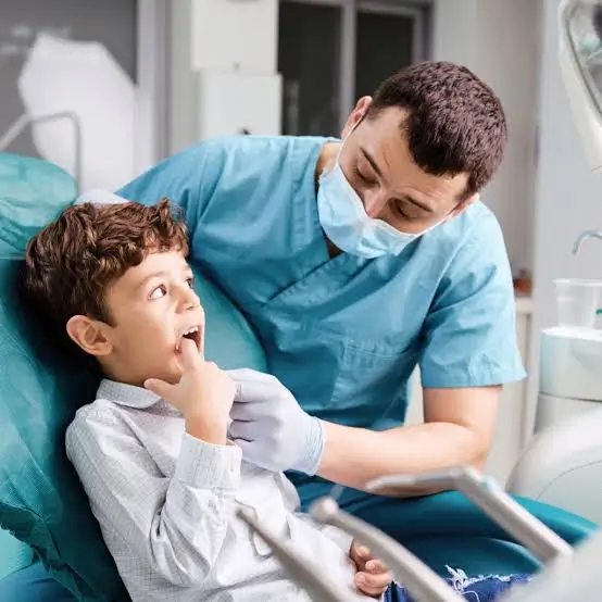 Pediatric dentist examining a young boy's teeth during a routine dental checkup in a modern dental clinic.