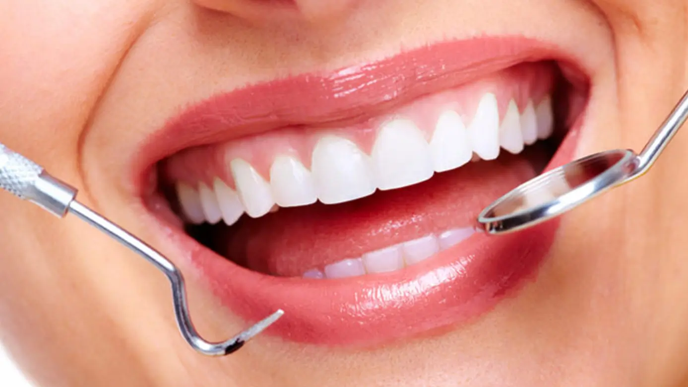 Close-up of a healthy smile during a professional dental examination with a dental mirror and explorer in a modern dental clinic.