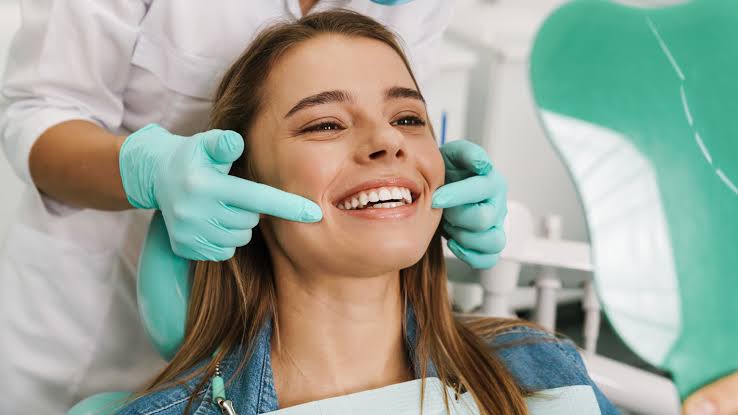 Female patient smiling during a cosmetic dental consultation while a dentist evaluates her smile for aesthetic dental treatment.