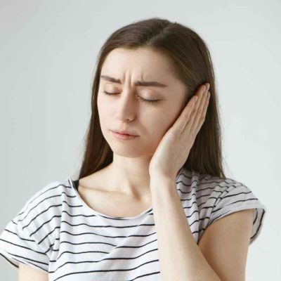 Woman experiencing severe ear pain while holding her ear, seeking expert pain management treatment.