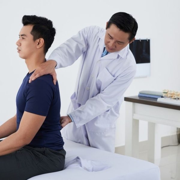 Doctor assessing patient posture and spinal alignment during examination