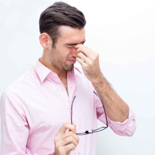 Man pressing the bridge of his nose due to sinus pain or facial pressure