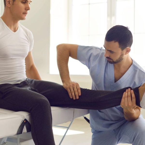 Physiotherapist examining leg movement during rehabilitation therapy